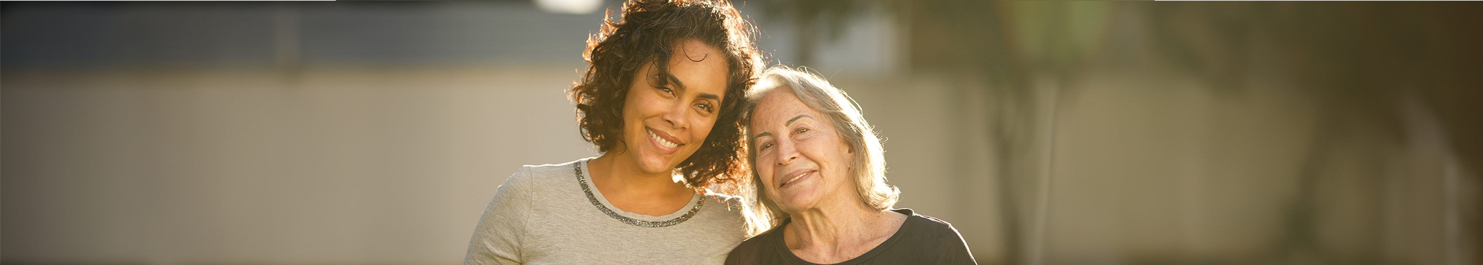 An Aboriginal woman in her 40s and a wise older woman in her 60s, smiling together, empowered to have a free breast screen.